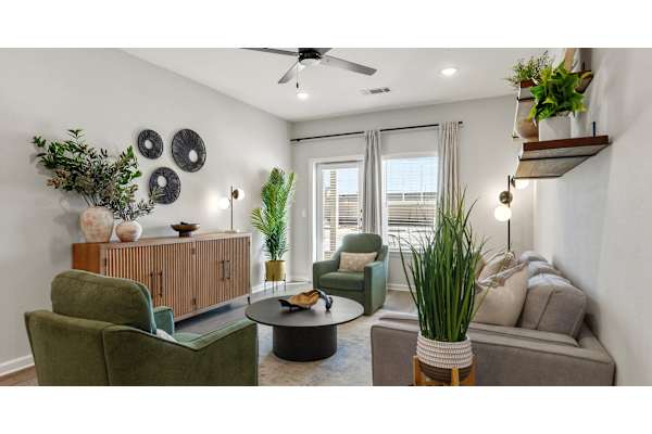 A living room with a green chair, a brown sofa, and a ceiling fan.